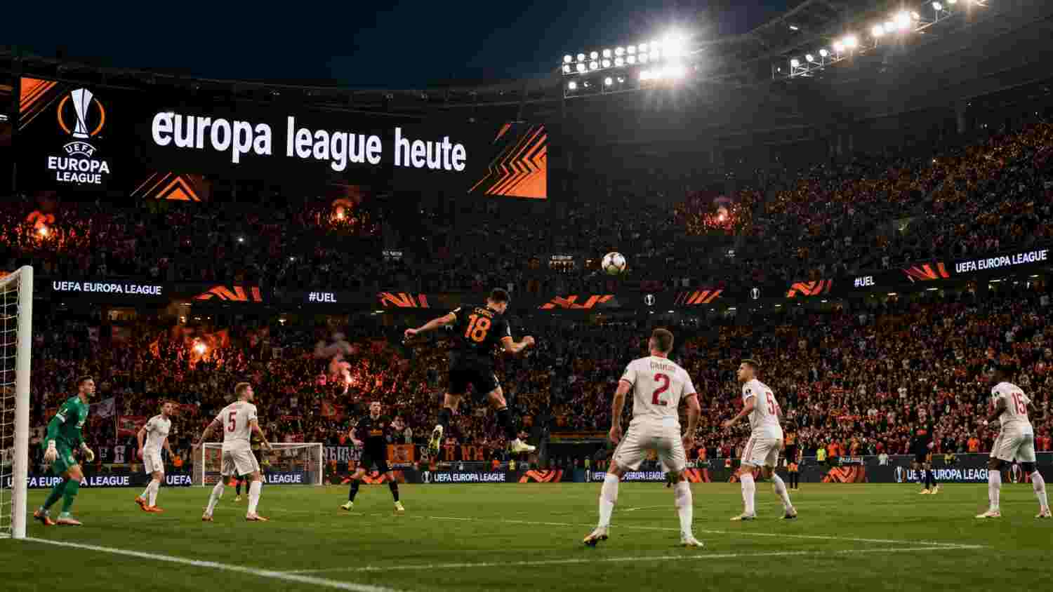Europa League heute live: Dramatische Szene im vollbesetzten Stadion mit Kopfballduell und UEFA-Branding unter Flutlicht